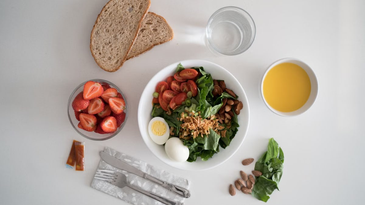 Top view of a nutritious breakfast with salad, eggs, bread, and juice, perfect for a healthy start.